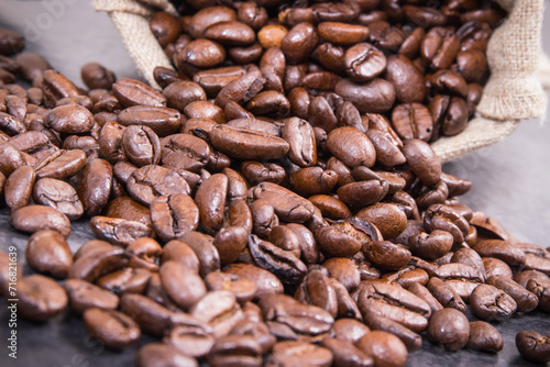 Heap of dark roasted fragrant coffee beans in jute bag