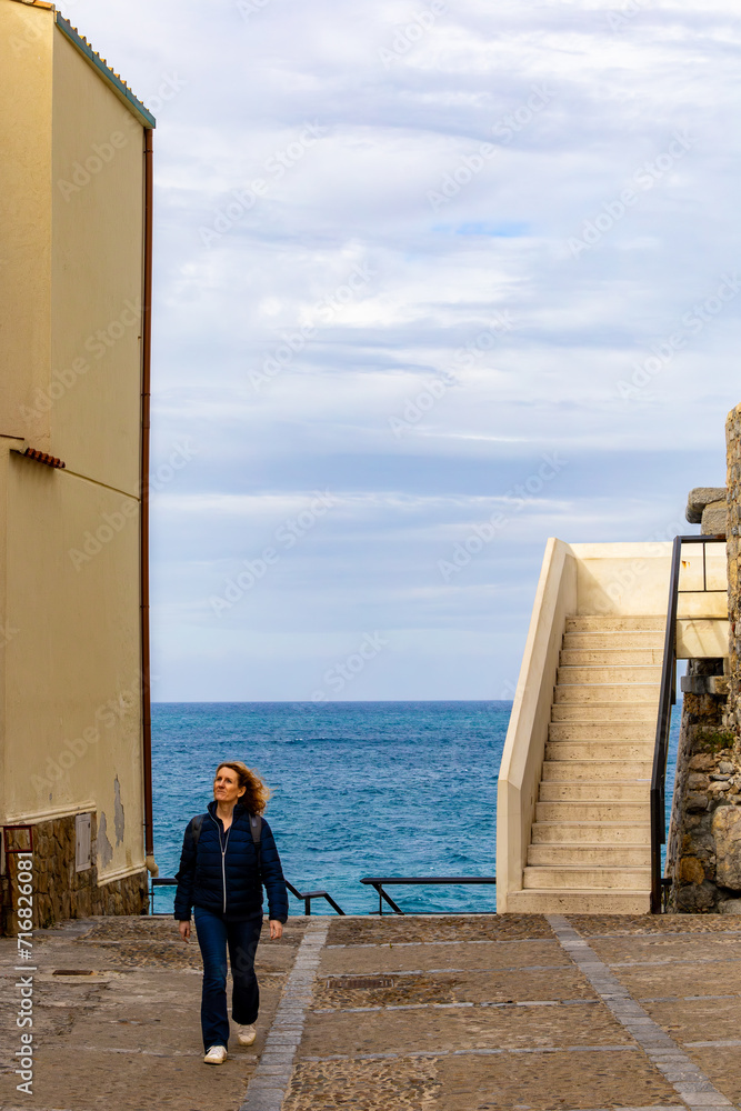 Cefalu, Sicily, Italy A woman tourist standing at the Bastione di Capo Marchiafava, a popular viewpoint over the Mediterranean Sea. Cefalu, Sicily, Italy A woman tourist standing at the Bastione di Capo Marchiafava, a popular viewpoint over the Mediterranean Sea.
