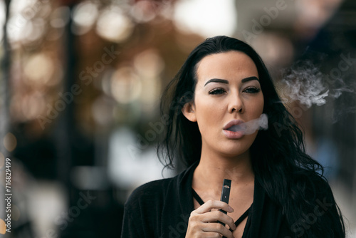 Adult Female Exhales Vapor With An E-Cigarette photo