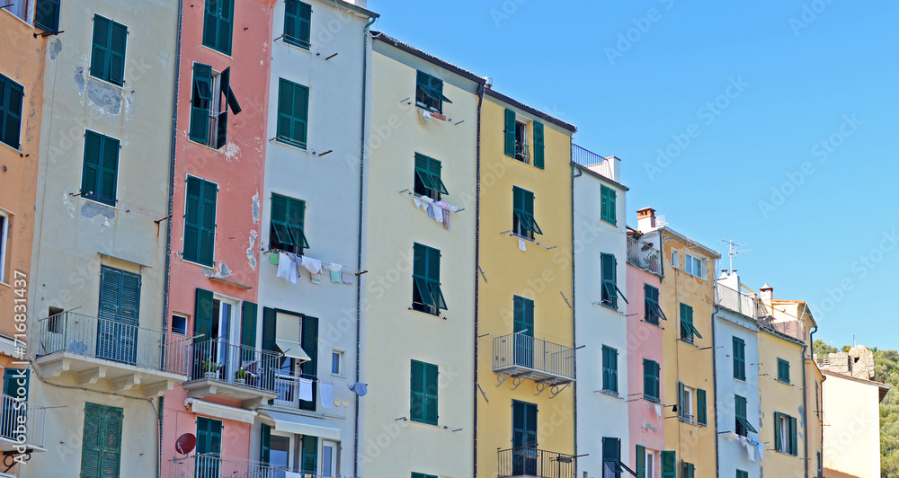 Typical colourful high and narrow houses with dark green shutters in Portovenere in the Gulf of the Poets at the Ligurian coast, Italy, on a bright September day with blue sky