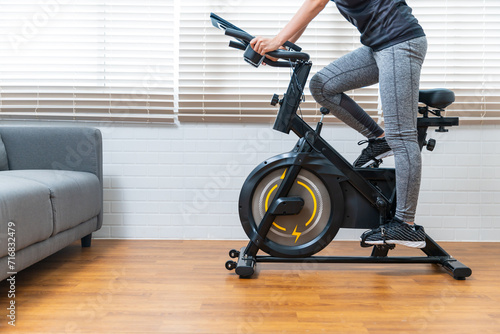 Asian female beautiful women cycle at home using stationary exercise bike, healthy lifestyle  workout exercise daily leisure activity routine, happy smiling with enjoyment.