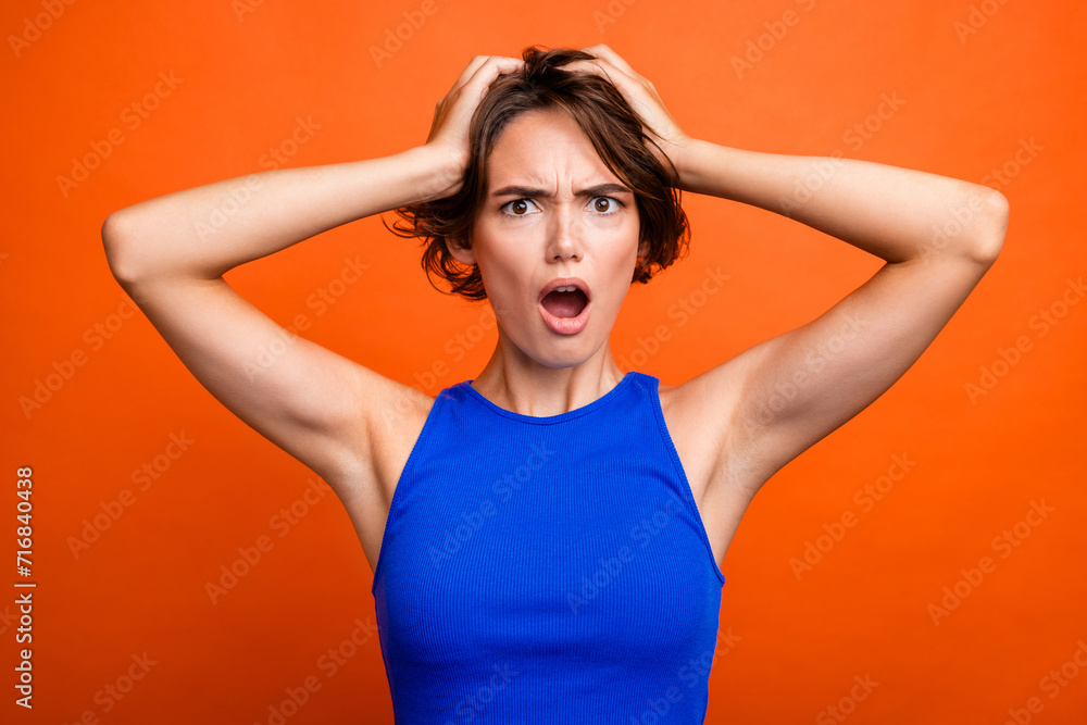 Photo of stressed shocked girl dressed blue top arms head open mouth isolated orange color background