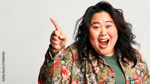  Asian woman pointing finger at empty space for editing isolated on light background
