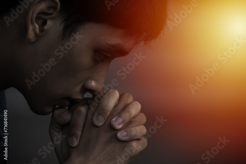A man praying and close your eyes in praying. Prayer to pray. A young man is holding palms by his lips, whispering a prayer, and asking.
