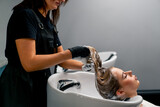 a hairdresser washing off dye from a client's hair during a care procedure in a beauty salon