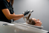 a hairdresser washing off dye from a client's hair during a care procedure in a beauty salon