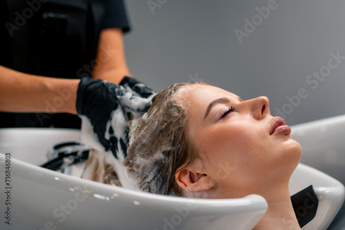 close-up of a hairdresser washing off dye from a client's hair during a care procedure in a salon photo
