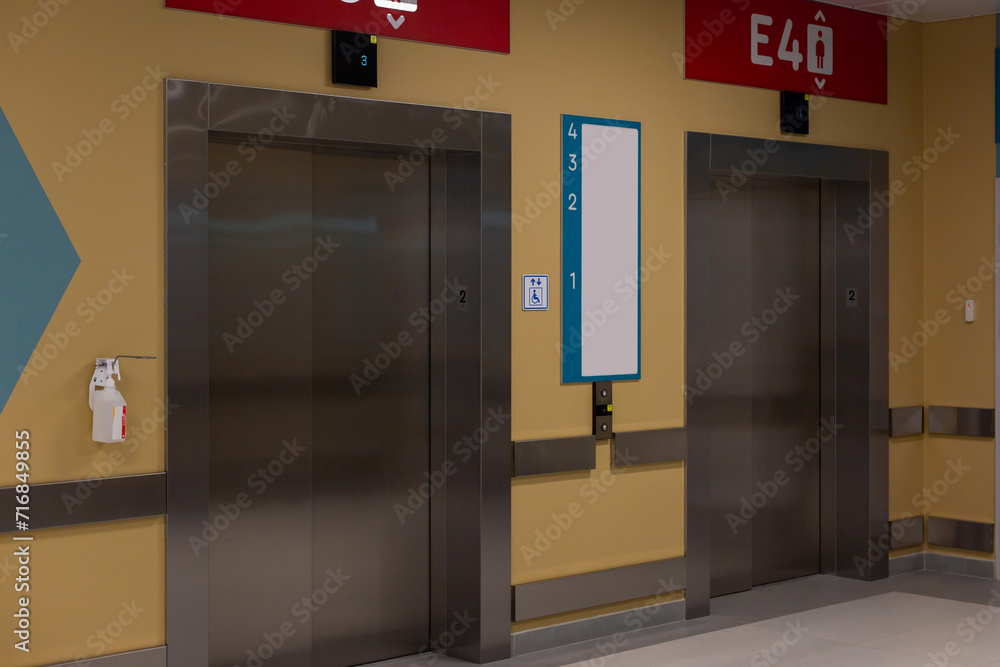 Modern elevator doors with red directional signs in a corridor Modern elevator doors with red directional signs in a corridor