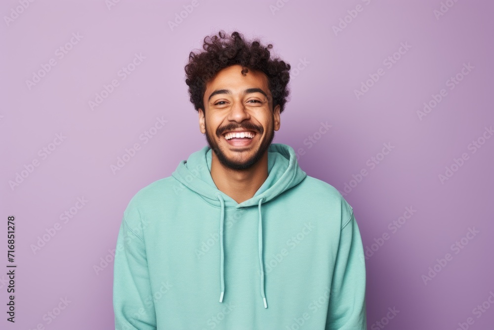 Portrait of a grinning indian man in his 20s wearing a zip-up fleece hoodie against a solid pastel color wall. AI Generation Portrait of a grinning indian man in his 20s wearing a zip-up fleece hoodie against a solid pastel color wall. AI Generation