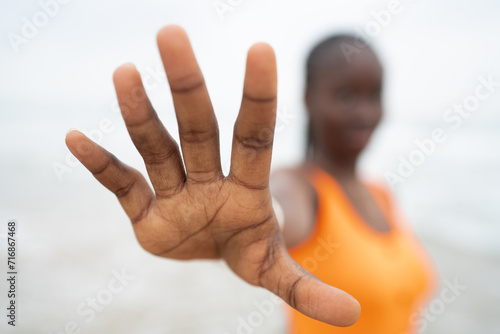 Content black woman showing stop gesture on seashore photo