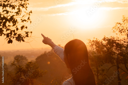 Medium shot Asian female standing against sunset in golden hour on Autumn vacation day, young cheerful happy lifestyle freedom traveling alone in nature outdoor activity, tourist woman enjoy carefree