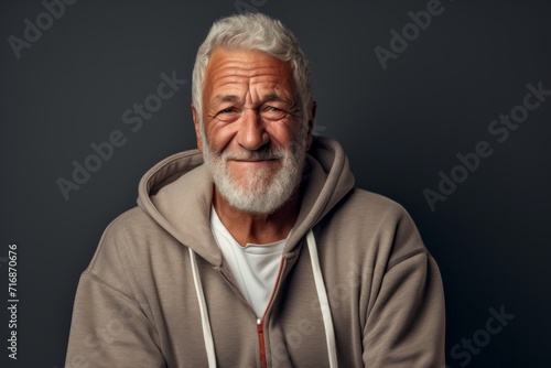 Portrait of a joyful man in his 70s wearing a zip-up fleece hoodie against a bare monochromatic room. AI Generation