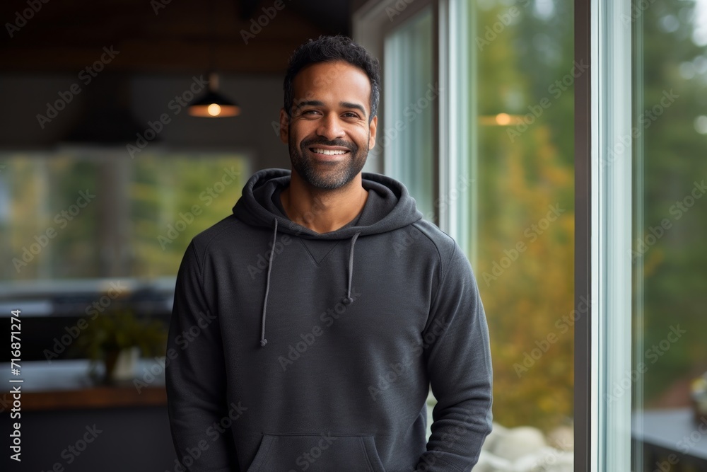 Portrait of a happy indian man in his 30s dressed in a comfy fleece pullover against a stylized simple home office background. AI Generation Portrait of a happy indian man in his 30s dressed in a comfy fleece pullover against a stylized simple home office background. AI Generation