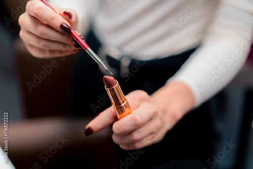 close-up of a make-up artist uses a lipstick brush to apply cosmetic products to a beauty salon