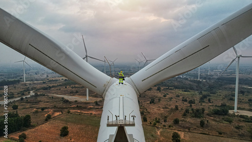 Windmill engineer wearing PPE standing on wind turbine.  engineer feel success after good work. He standing a top of windmill.
