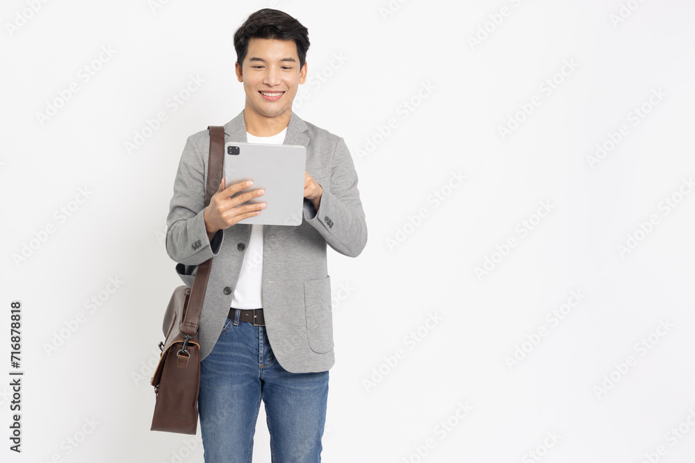 Happy young Asian businessman in suit with bag using tablet computer on hand isolated on white background, Technology of business concept Happy young Asian businessman in suit with bag using tablet computer on hand isolated on white background, Technology of business concept