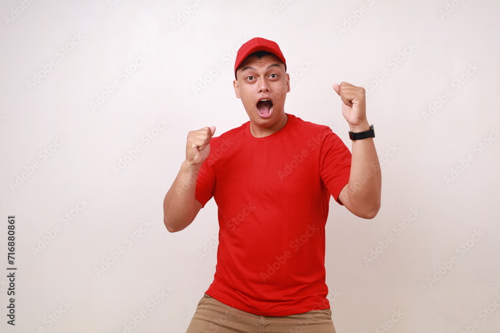 Naklejka premium Handsome young asian courier standing while celebrating his success against white background