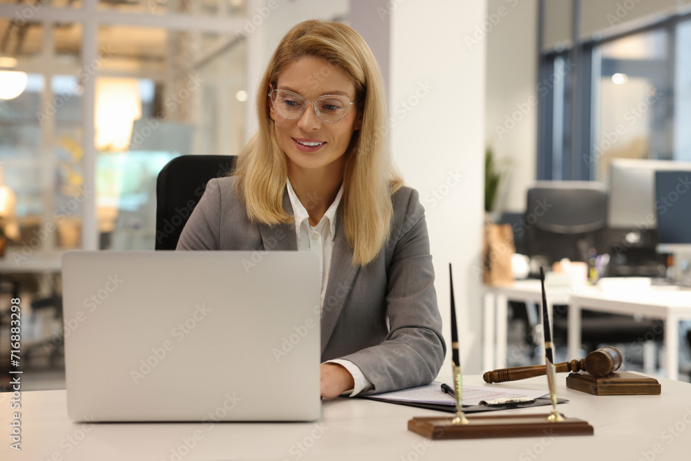 Smiling lawyer working with laptop at table in office Smiling lawyer working with laptop at table in office