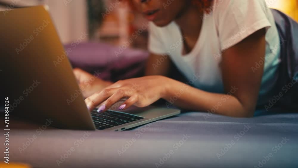 Young woman typing on laptop while lying in bed, social media life addiction Young woman typing on laptop while lying in bed, social media life addiction