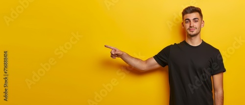 Studio photo of young man standing on left isolated on yellow background pointing at blank space for your advertisement in black t shirt seeing something unusual or unexpected. Generative ai photo