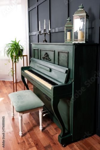 a dark green piano with a light chair against a dark blue wall. a ready-made decoration for a wedding photo shoot. a real colored piano in a spacious room