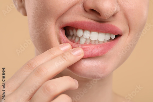Woman showing her clean teeth on beige background  closeup