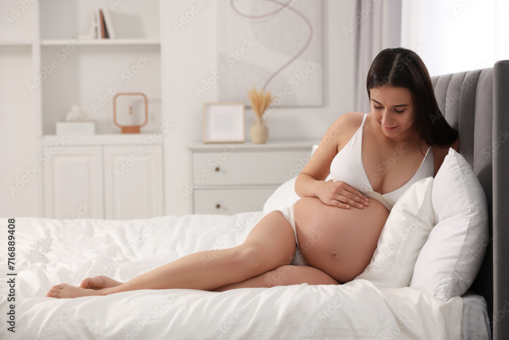 Beautiful pregnant woman in stylish comfortable underwear on bed at home Beautiful pregnant woman in stylish comfortable underwear on bed at home