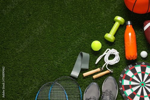Different sports equipment on green grass  flat lay. Space for text