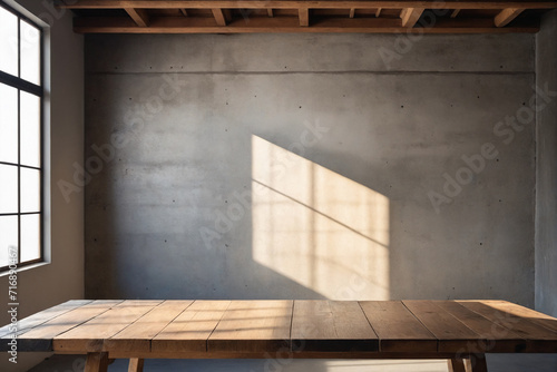 Empty copy space on a wooden tabletop against the cement loft wall with shadow and daylight indoors