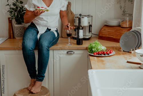 Close-up of hands preparing snack sandwich and wine in kitchen photo