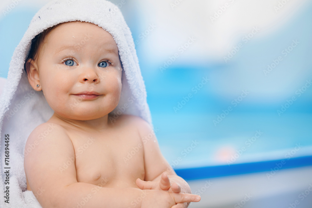 Portrait happy baby girl in white towel after swimming lessons in pool, blur background Portrait happy baby girl in white towel after swimming lessons in pool, blur background