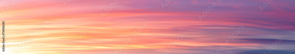 Vibrant extra wide panoramic sky. Fantasy banner sky. Rich colors. Daytime sunset beauty. Fiery glowing heavenly sky with gradient colors. Red, pink, orange, blue, yellow. Horizontal long soft clouds