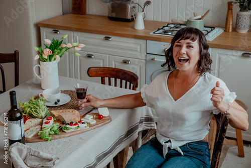 Beautiful girl with dark hair in the kitchen with wine and food photo