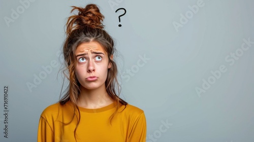 Portrait of confused young woman with question mark above her head on grey background