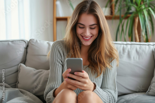 Happy woman with light brown hair looking at her smartphone screen in a living room