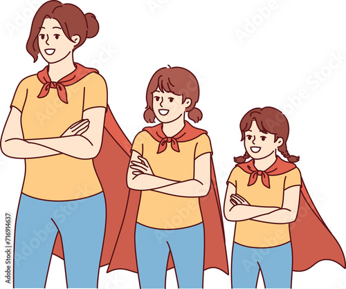 Obraz na płótnie Mom and daughters in superhero capes smile, feeling unity and courage, stand with arms crossed