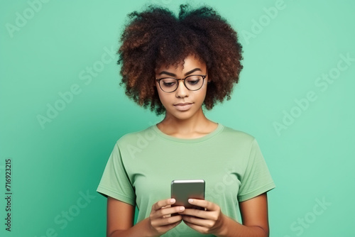 Portrait of toothy beaming nice African American woman wear stylish t-shirt in eyewear hold smartphone arm in pocket isolated on green color background