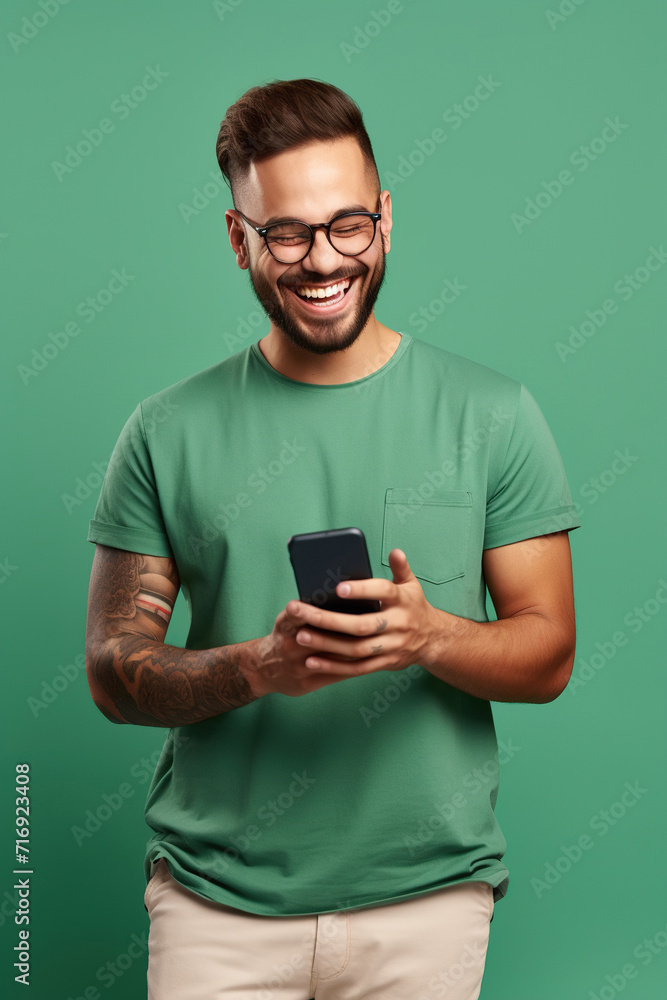 Portrait of toothy beaming nice person wear stylish t-shirt in eyewear hold smartphone arm in pocket isolated on green color background Portrait of toothy beaming nice person wear stylish t-shirt in eyewear hold smartphone arm in pocket isolated on green color background