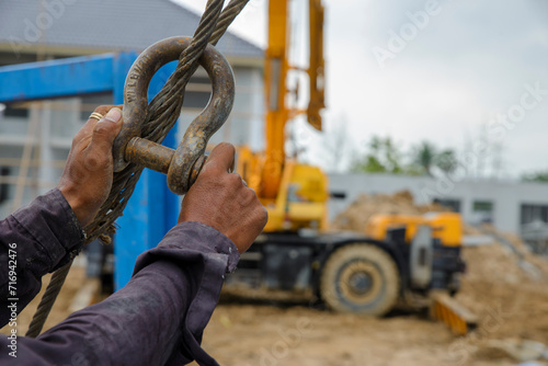 Man hand pulling metal sling of crane to lift cement platform at construction site. © prachid