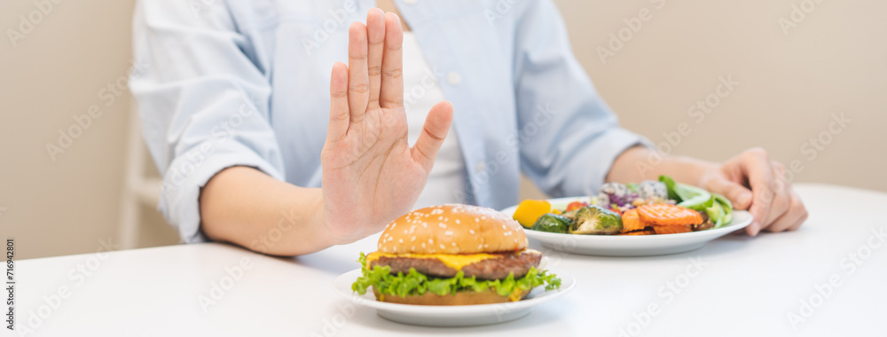 Diet concept, asian young woman hand reject eat burger, hamburger on plate, push out or deny to eat fast, junk food choose green vegetable salad, girl eat low fat for good healthy, getting weight loss Diet concept, asian young woman hand reject eat burger, hamburger on plate, push out or deny to eat fast, junk food choose green vegetable salad, girl eat low fat for good healthy, getting weight loss
