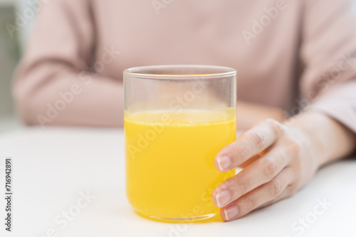 Close up young woman hand holding glass of water after putting or dropping yellow effervescent tablet, pain pill, painkiller medicine, aspirin for treatment, take vitamin c for hangover, health care.