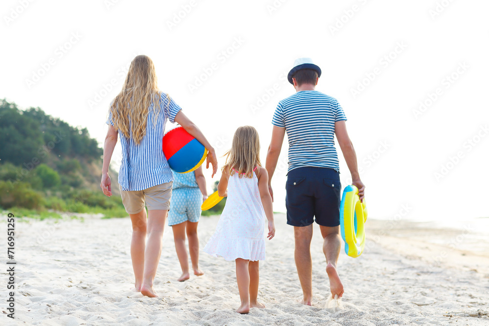 Young family having fun running on beach at sunset.