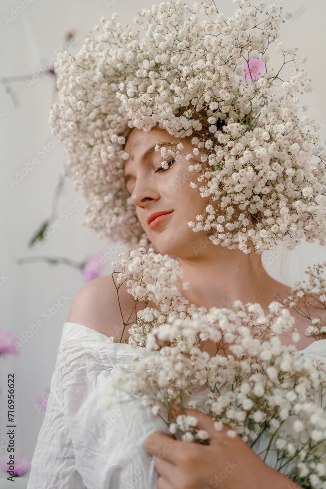 Portrait of sensual blond woman with flowers. Beautiful girl with flowers in her hair. Summer Beauty. Art in a contemporary style. A gypsophila wreath on a white background. Perfume, cosmetics concept Portrait of sensual blond woman with flowers. Beautiful girl with flowers in her hair. Summer Beauty. Art in a contemporary style. A gypsophila wreath on a white background. Perfume, cosmetics concept