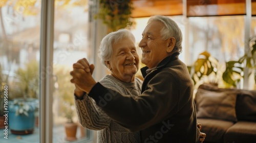 Happy Senior Couple Dancing Having Fun At Home On Weekend. Husband And Wife Enjoying Retired Life Having Date In Living Room. Retirement Hobby And Leisure For Mature Spouses Concept