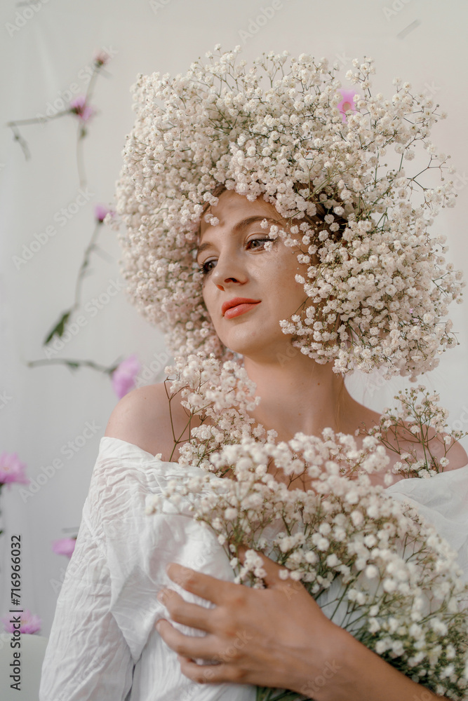 Portrait of sensual blond woman with flowers. Beautiful girl with flowers in her hair. Summer Beauty. Art in a contemporary style. A gypsophila wreath on a white background. Perfume, cosmetics concept Portrait of sensual blond woman with flowers. Beautiful girl with flowers in her hair. Summer Beauty. Art in a contemporary style. A gypsophila wreath on a white background. Perfume, cosmetics concept