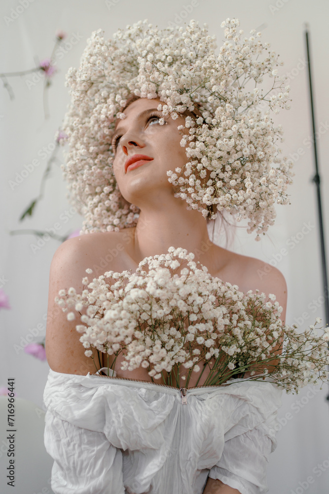 Portrait of sensual blond woman with flowers. Beautiful girl with flowers in her hair. Summer Beauty. Art in a contemporary style. A gypsophila wreath on a white background. Perfume, cosmetics concept Portrait of sensual blond woman with flowers. Beautiful girl with flowers in her hair. Summer Beauty. Art in a contemporary style. A gypsophila wreath on a white background. Perfume, cosmetics concept
