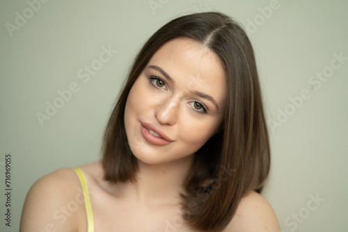 portrait of a young beautiful woman with dark short hair looking at the camera in yellow lingerie