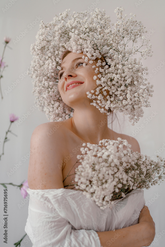 Portrait of sensual blond woman with flowers. Beautiful girl with flowers in her hair. Summer Beauty. Art in a contemporary style. A gypsophila wreath on a white background. Perfume, cosmetics concept Portrait of sensual blond woman with flowers. Beautiful girl with flowers in her hair. Summer Beauty. Art in a contemporary style. A gypsophila wreath on a white background. Perfume, cosmetics concept