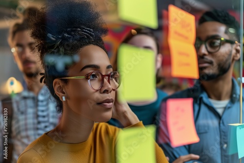 Diverse Team Brainstorms Ideas Using Sticky Notes On Glass Wall