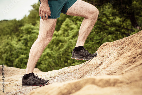 Man runs along a mountain path closeup feet sneakers